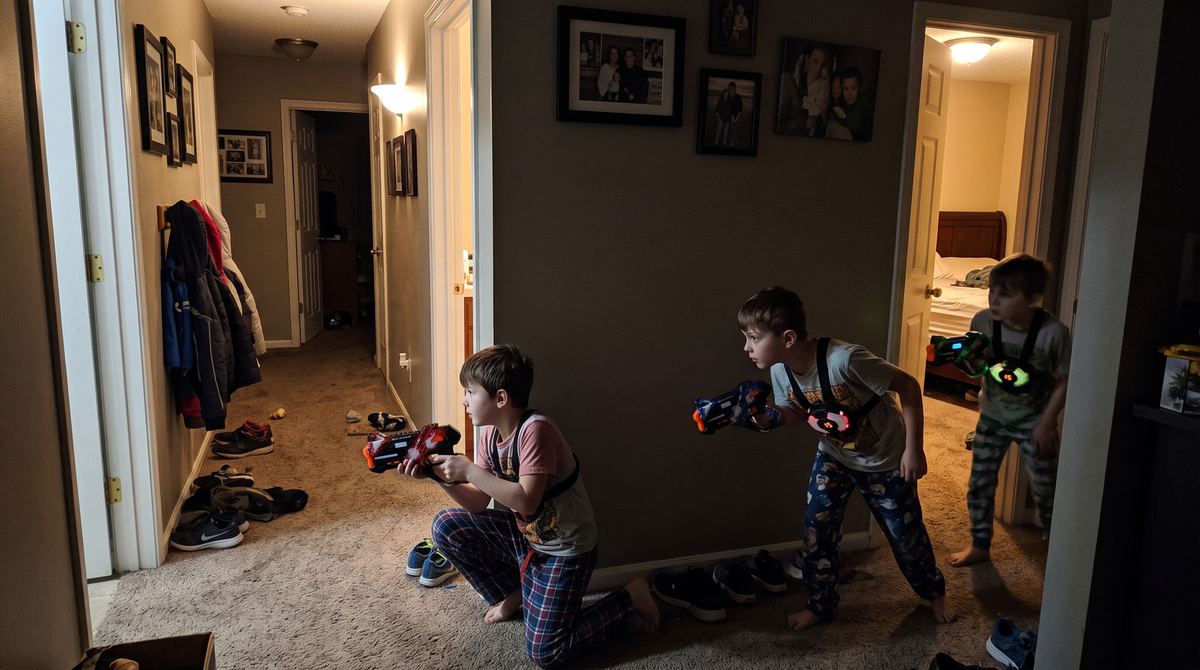 Kids playing BEAMBLITZ laser tag in a hallway at night